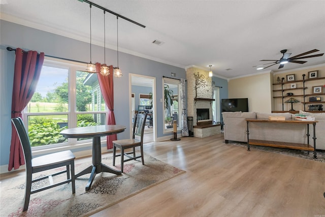 113 Friendship Ln, Beebe, AR 72012 - dining space featuring ornamental molding, light wood-type flooring, a fireplace, and ceiling fan