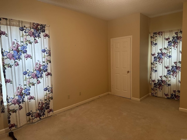 spare room featuring light carpet and baseboards