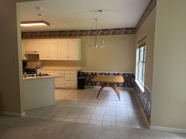 kitchen featuring a textured ceiling, white cabinetry, under cabinet range hood, and light colored carpet