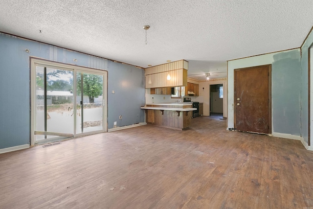 27 Arbor Oaks Dr, Sherwood, AR 72120 - kitchen with a peninsula, electric range, wood finished floors, light countertops, and a kitchen breakfast bar