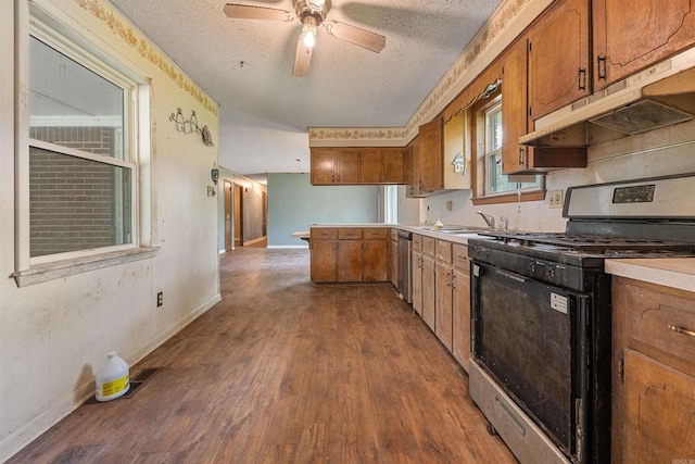 27 Arbor Oaks Dr, Sherwood, AR 72120 - kitchen with black gas range, under cabinet range hood, brown cabinetry, a peninsula, and a textured ceiling