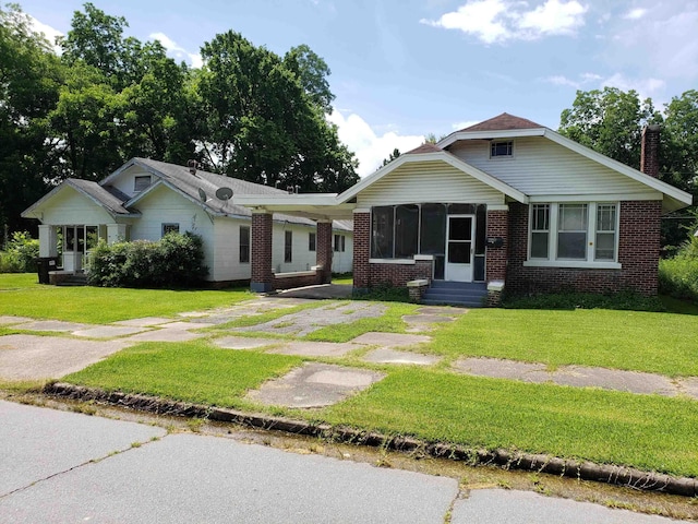 1504 W 18th Ave, Pine Bluff, AR 71603 - view of front of house with brick siding, entry steps, a front yard, driveway, and a chimney
