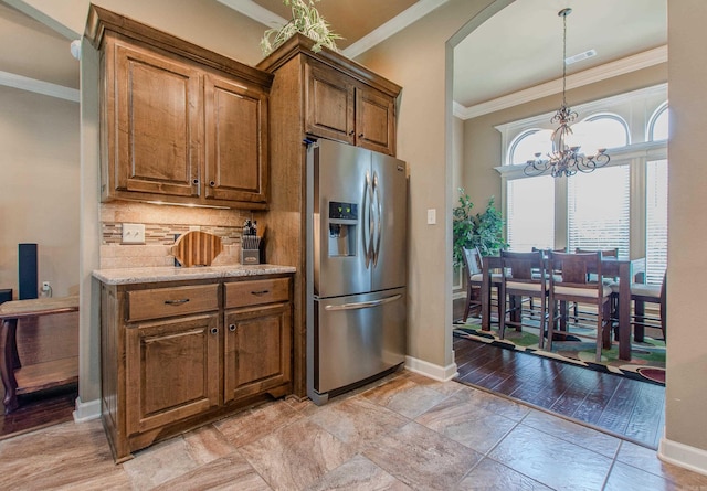 2148 Avondale Dr, Benton, AR 72019 - kitchen with stainless steel fridge, crown molding, brown cabinets, a chandelier, and arched walkways