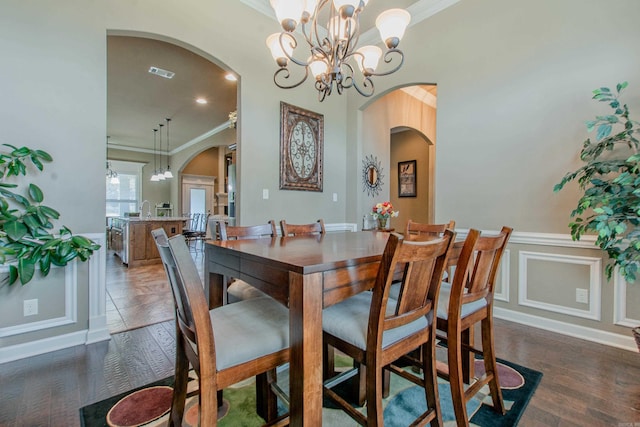 2148 Avondale Dr, Benton, AR 72019 - dining area with arched walkways, ornamental molding, a chandelier, dark wood finished floors, and a wainscoted wall