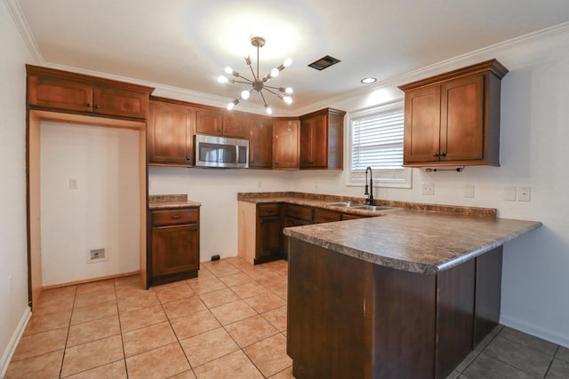 1206 Ryan Ln, Paragould, AR 72450 - kitchen featuring stainless steel microwave, dark countertops, a peninsula, a chandelier, and crown molding