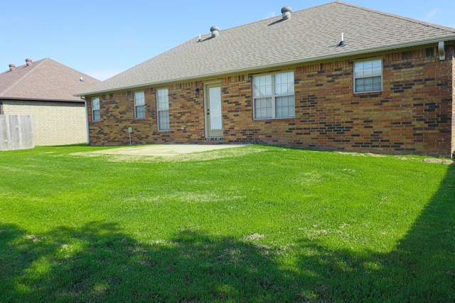 1206 Ryan Ln, Paragould, AR 72450 - rear view of property with brick siding, a patio area, roof with shingles, and a yard