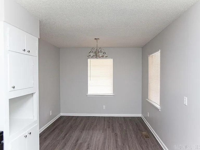 4207-4209 Moss St, North Little Rock, AR 72118 - unfurnished dining area with a chandelier, dark wood-style flooring, a textured ceiling, and plenty of natural light