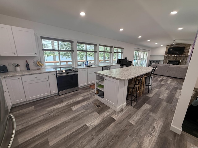 716 S Shore Dr, Horseshoe Bend, AR 72512 - kitchen featuring stainless steel appliances, recessed lighting, white cabinets, a breakfast bar, and a large fireplace