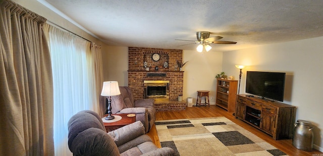 1000 Waverly Rd, Mountain Home, AR 72653 - living room with wood finished floors, a ceiling fan, a fireplace, and a textured ceiling