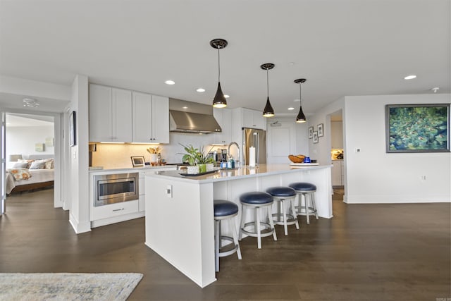 3700 Cantrell Rd Unit 1002, Little Rock, AR 72202 - kitchen featuring wall chimney range hood, stainless steel appliances, light countertops, white cabinets, and an island with sink