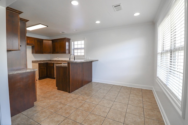 kitchen with a peninsula, crown molding, light tile patterned floors, light stone countertops, and recessed lighting
