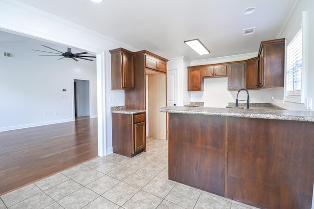 kitchen featuring crown molding, ceiling fan, a peninsula, light stone countertops, and light tile patterned flooring