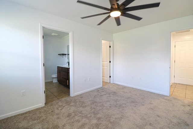 unfurnished bedroom with carpet, tile patterned floors, ensuite bathroom, and a ceiling fan