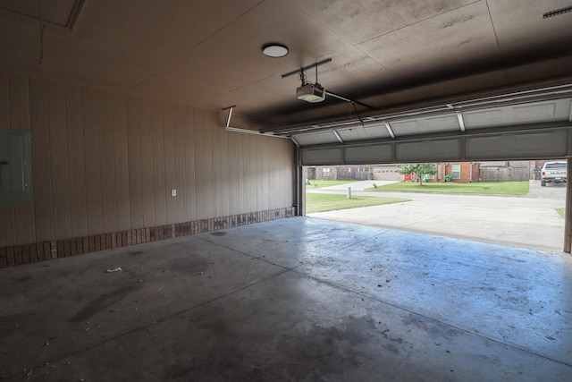 garage featuring electric panel, a garage door opener, and wooden walls