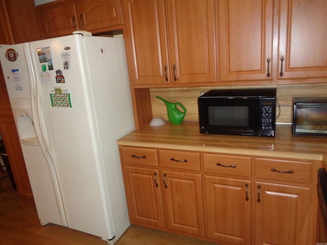 2 Wellington Ct, Little Rock, AR 72227 - kitchen featuring white fridge with ice dispenser, black microwave, light countertops, decorative backsplash, and brown cabinets