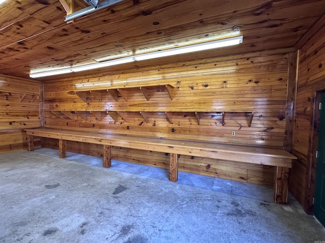relaxing sauna / steam room with wood walls and unfinished concrete floors