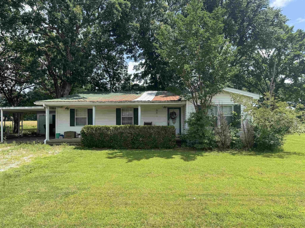 single story home featuring a carport, a front yard, and a metal roof