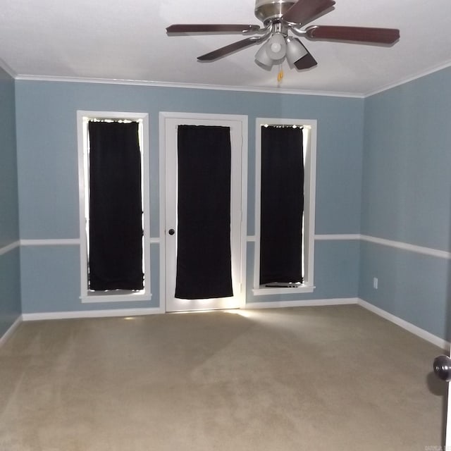 carpeted spare room with a ceiling fan and crown molding