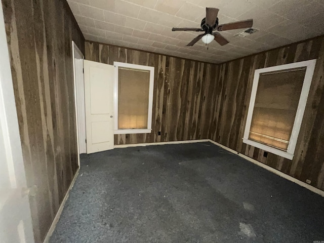 unfurnished room featuring wood walls, ceiling fan, and carpet flooring