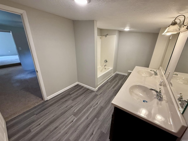 131 N Pine St, Salem, AR 72576 - full bath featuring a textured ceiling, double vanity, wood finished floors, and tub / shower combination