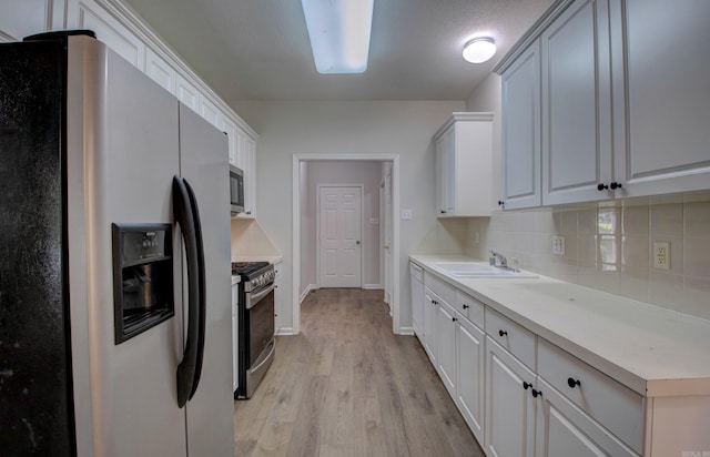 12825 Westglen Dr, Little Rock, AR 72211 - kitchen featuring appliances with stainless steel finishes, decorative backsplash, light wood finished floors, light countertops, and white cabinetry
