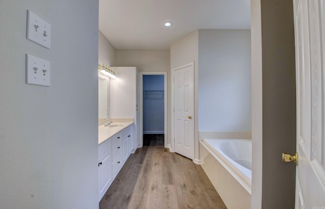 12825 Westglen Dr, Little Rock, AR 72211 - full bath featuring vanity, a bath, wood finished floors, a walk in closet, and recessed lighting