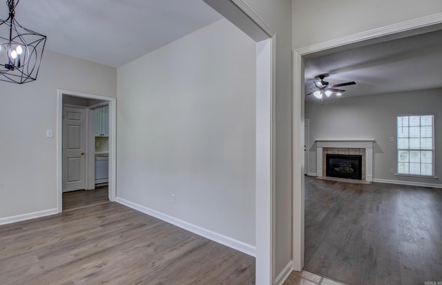 12825 Westglen Dr, Little Rock, AR 72211 - unfurnished living room featuring wood finished floors, a chandelier, ceiling fan, and a tiled fireplace