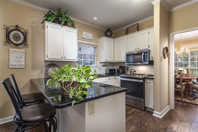 1315 Gleneagles Ct, Little Rock, AR 72211 - kitchen featuring appliances with stainless steel finishes, a peninsula, a chandelier, white cabinets, and crown molding