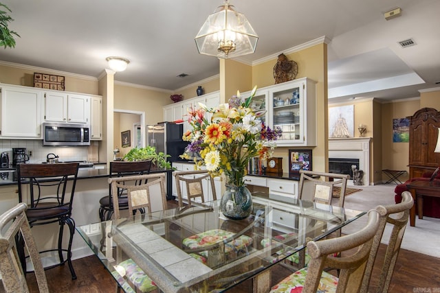 1315 Gleneagles Ct, Little Rock, AR 72211 - dining room featuring dark wood-style floors, crown molding, a fireplace, and a chandelier