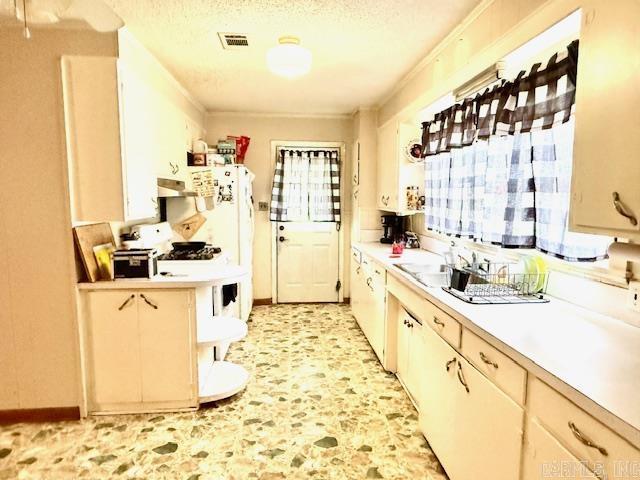 119 N 20th St, Arkadelphia, AR 71923 - kitchen featuring light countertops, a textured ceiling, under cabinet range hood, and freestanding refrigerator