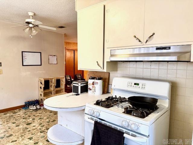 119 N 20th St, Arkadelphia, AR 71923 - kitchen featuring white range with gas cooktop, under cabinet range hood, light countertops, a ceiling fan, and a textured ceiling