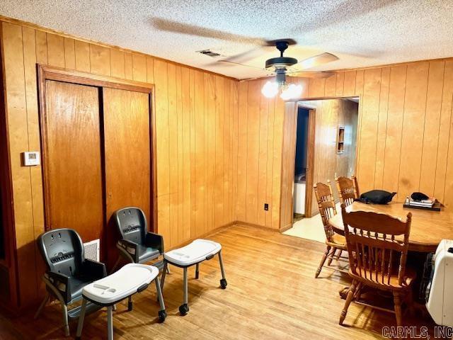 119 N 20th St, Arkadelphia, AR 71923 - dining room with a ceiling fan, light wood finished floors, a textured ceiling, and wood walls