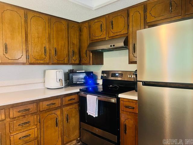 4 Brookway Ln, North Little Rock, AR 72120 - kitchen with stainless steel appliances, under cabinet range hood, light countertops, and brown cabinetry