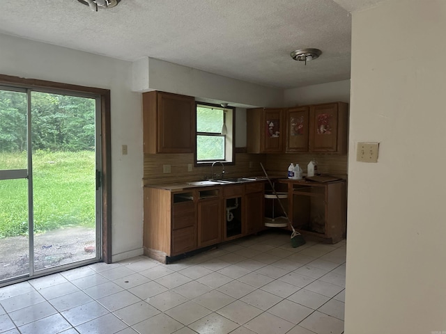 109 Randallwood Dr, Hot Springs Village, AR 71909 - kitchen with tasteful backsplash, a textured ceiling, light tile patterned flooring, and brown cabinetry