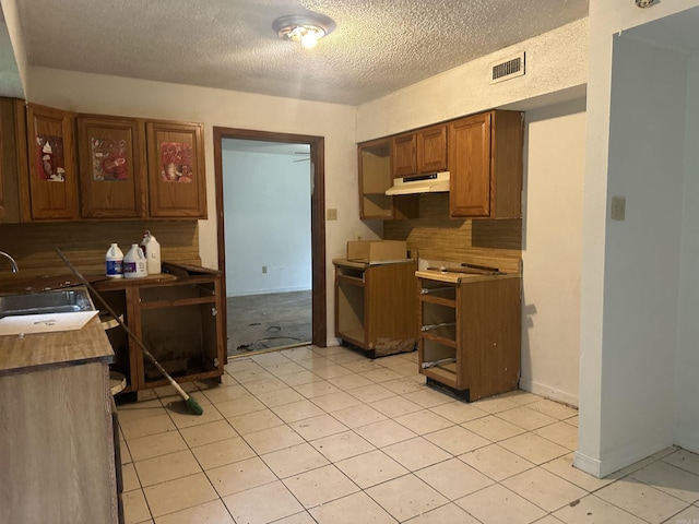 109 Randallwood Dr, Hot Springs Village, AR 71909 - kitchen with under cabinet range hood, a textured ceiling, decorative backsplash, and brown cabinetry