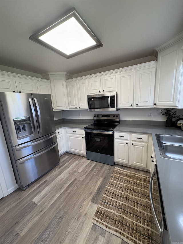 1901 N 19th St, Paragould, AR 72450 - kitchen with stainless steel appliances, light wood-type flooring, white cabinets, and dark countertops