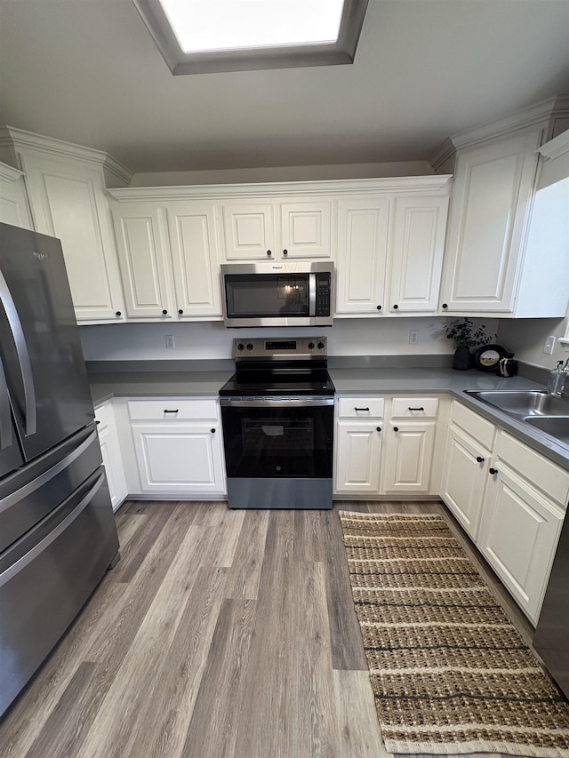 1901 N 19th St, Paragould, AR 72450 - kitchen featuring appliances with stainless steel finishes, wood finished floors, white cabinetry, and dark countertops