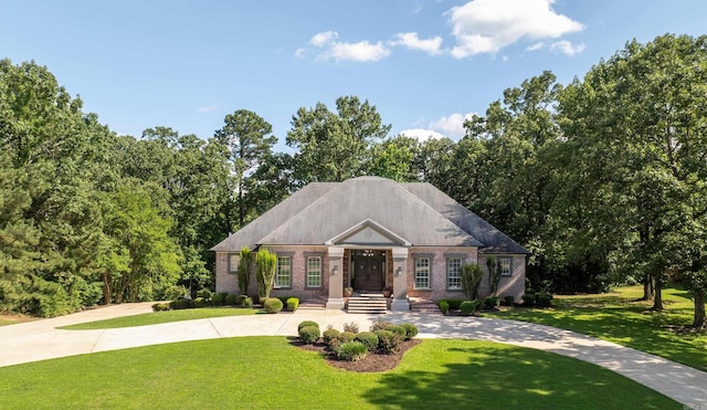 view of front facade with curved driveway, a front lawn, and brick siding
