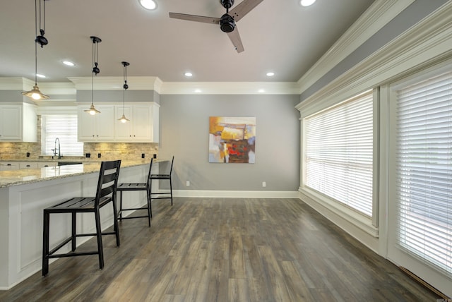 kitchen featuring ceiling fan, decorative backsplash, white cabinetry, dark wood finished floors, and crown molding