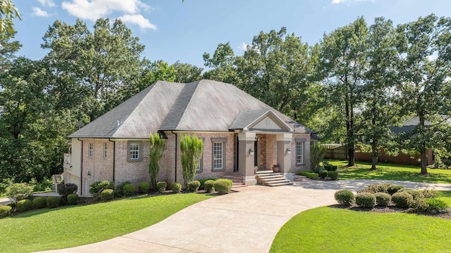 view of front facade featuring brick siding, a front yard, concrete driveway, and roof with shingles