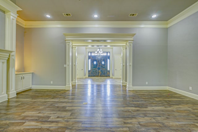 unfurnished living room with crown molding, a chandelier, dark wood-type flooring, ornate columns, and recessed lighting