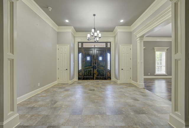 entrance foyer featuring ornate columns, a chandelier, crown molding, and recessed lighting