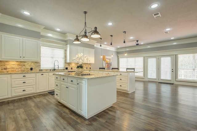 kitchen featuring ornamental molding, a center island, black electric cooktop, tasteful backsplash, and a peninsula