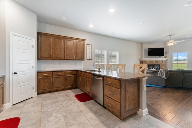 526 NW 62nd Ave, Bentonville, AR 72713 - kitchen with dishwasher, a ceiling fan, a peninsula, stone countertops, and a glass covered fireplace