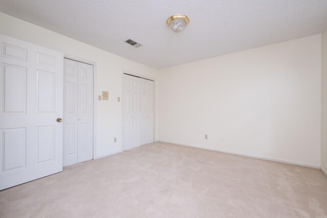 520 Cambridge Place Dr, Little Rock, AR 72227 - unfurnished bedroom with light colored carpet, two closets, and a textured ceiling