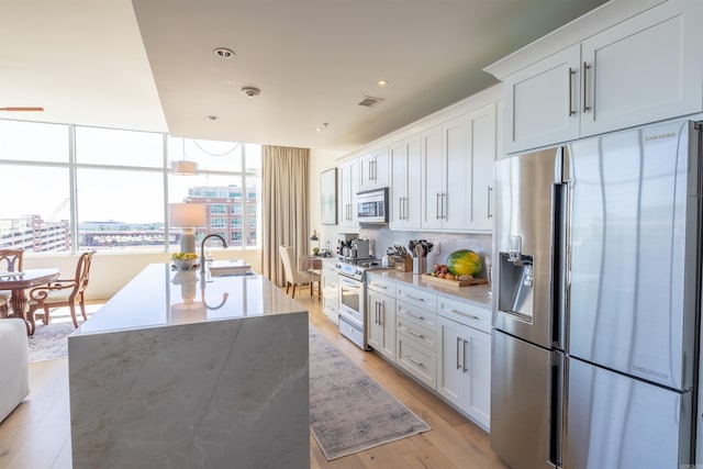 300 E 3rd St Unit 602, Little Rock, AR 72201 - kitchen with stainless steel appliances, white cabinets, tasteful backsplash, a kitchen island with sink, and recessed lighting