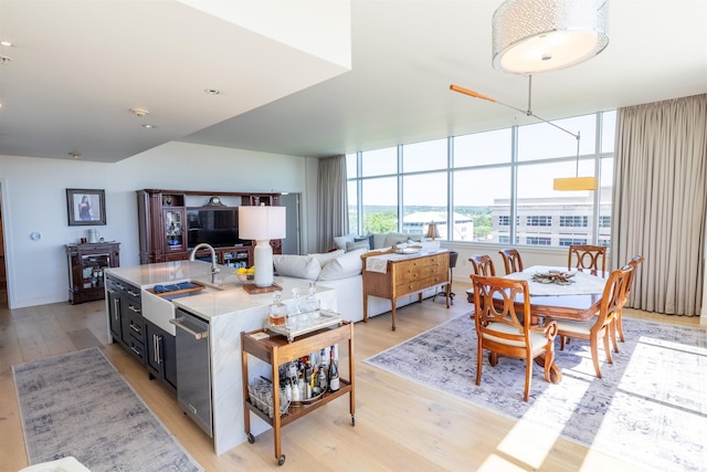 300 E 3rd St Unit 602, Little Rock, AR 72201 - kitchen featuring light wood finished floors, dishwasher, light countertops, dark cabinetry, and a kitchen island with sink