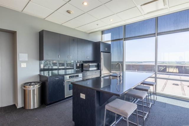300 E 3rd St Unit 602, Little Rock, AR 72201 - kitchen featuring stainless steel appliances, dark countertops, a breakfast bar, a center island with sink, and dark carpet