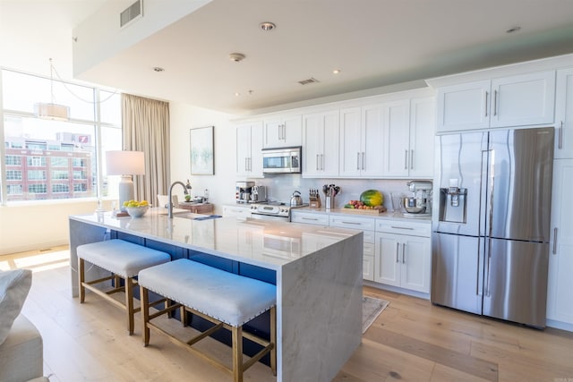 300 E 3rd St Unit 602, Little Rock, AR 72201 - kitchen featuring stainless steel appliances, white cabinets, light wood-type flooring, a large island, and a breakfast bar area