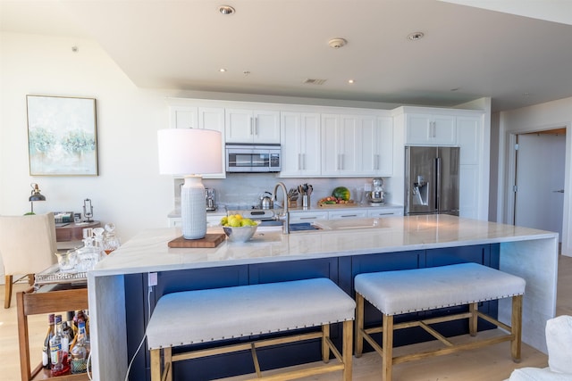 300 E 3rd St Unit 602, Little Rock, AR 72201 - kitchen with appliances with stainless steel finishes, white cabinets, a large island with sink, light stone countertops, and recessed lighting